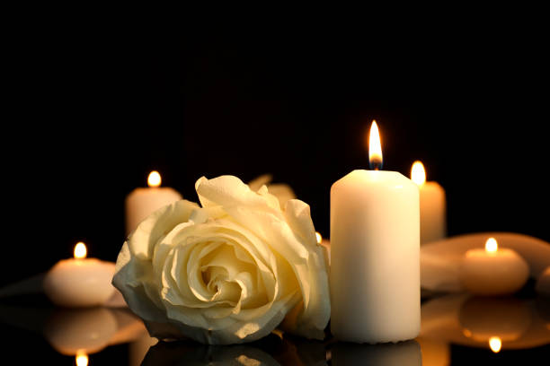 Candles and a white rose on a dark table